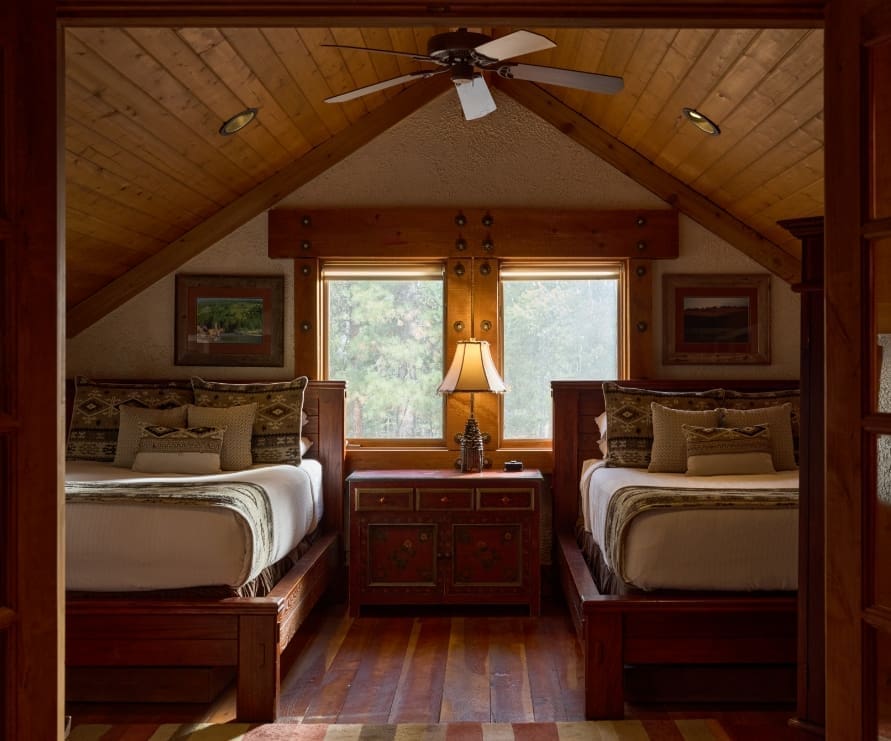 Inside view of a loft-style bedroom in a Big Timber home, featuring two full beds with western bedding
