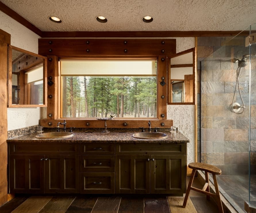 Inside view of a bathroom in a Big Timber home, with stone accents and a forest view outside the window