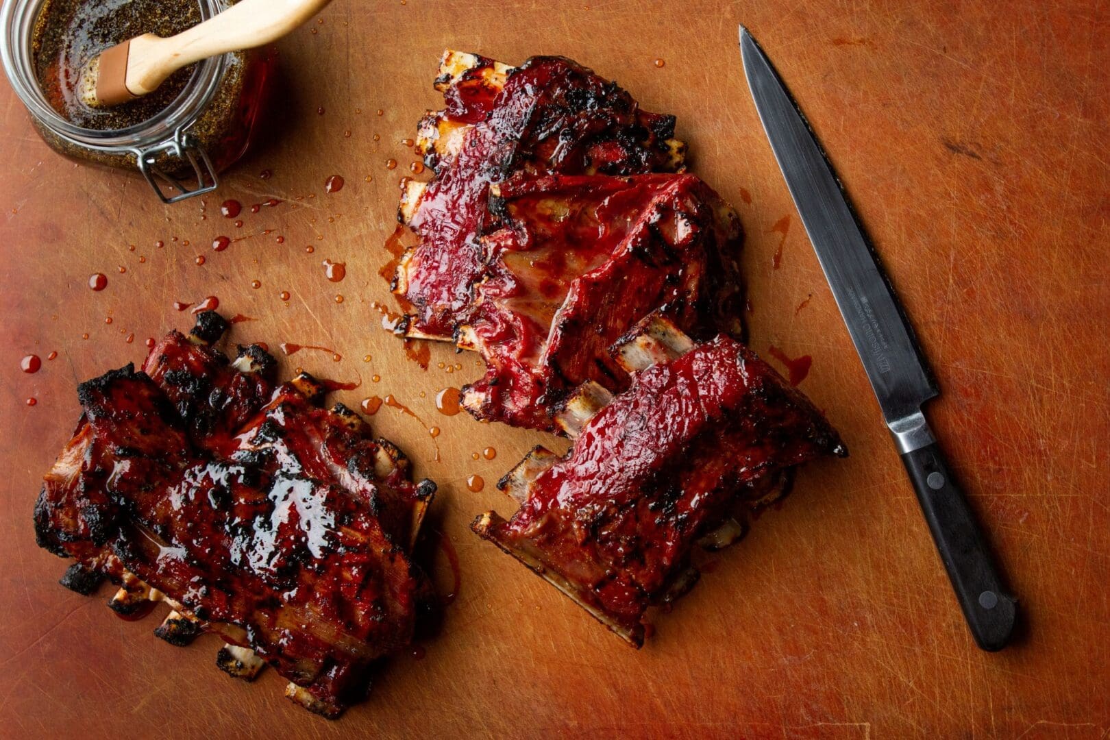 Ribs covered in barbeque sauce on a wooden cutting board