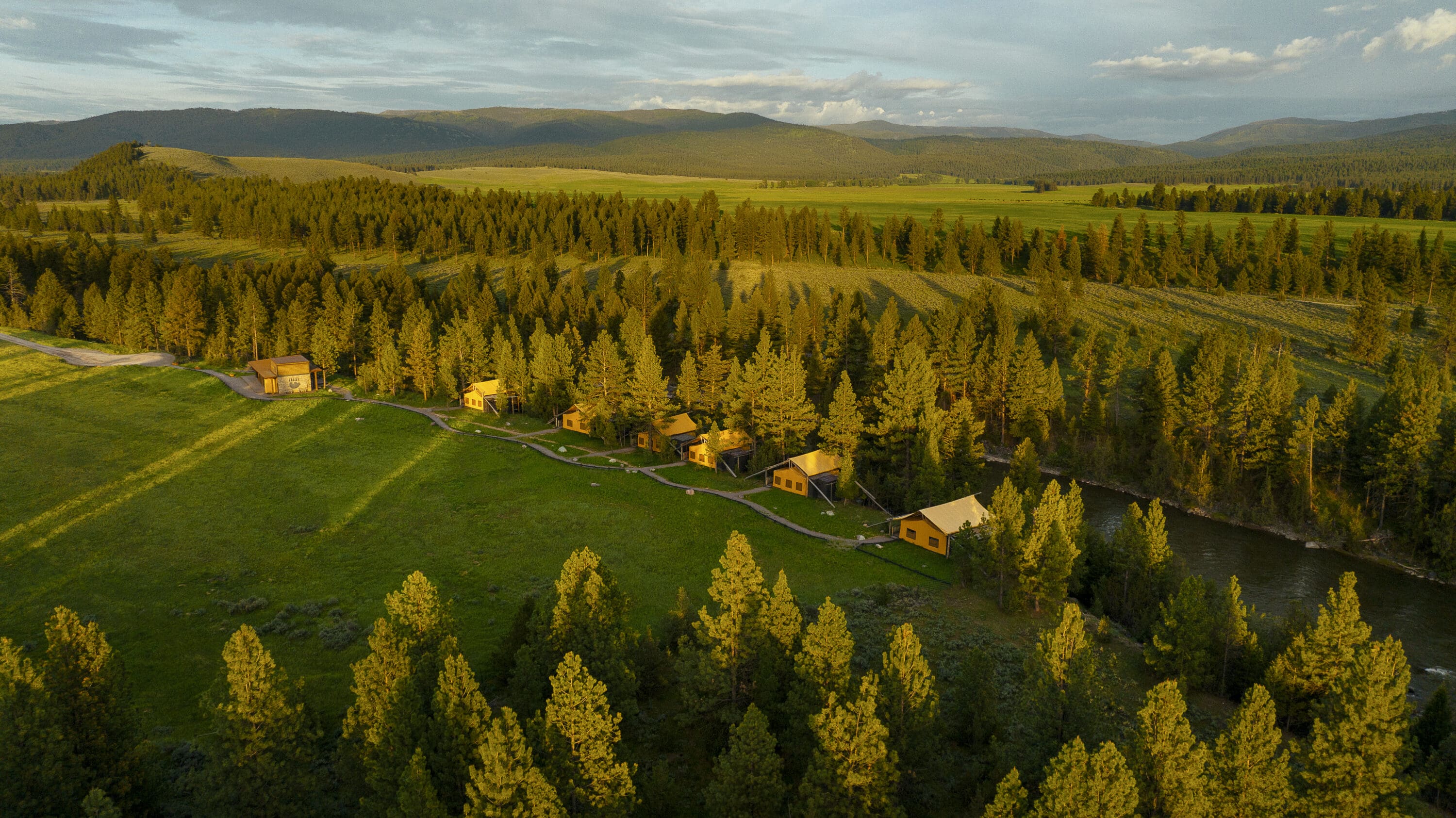 Overshot view of glamping tents with trees and mountains in the background.