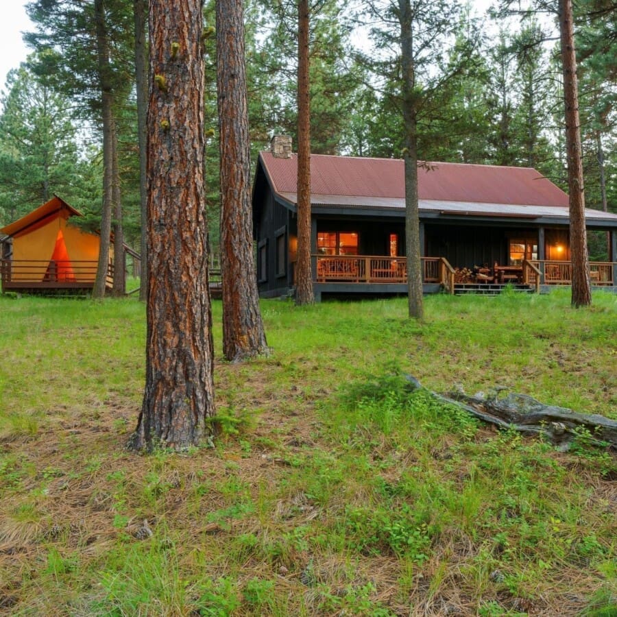 Wooden cabin next to a canvas glamping tent