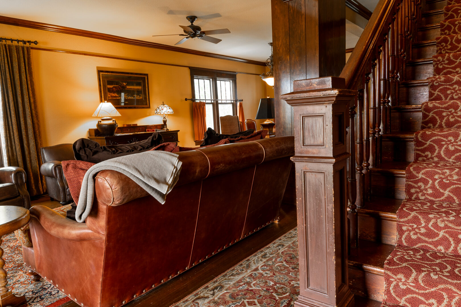 Western style living room with a leather chair and wooden staircase.