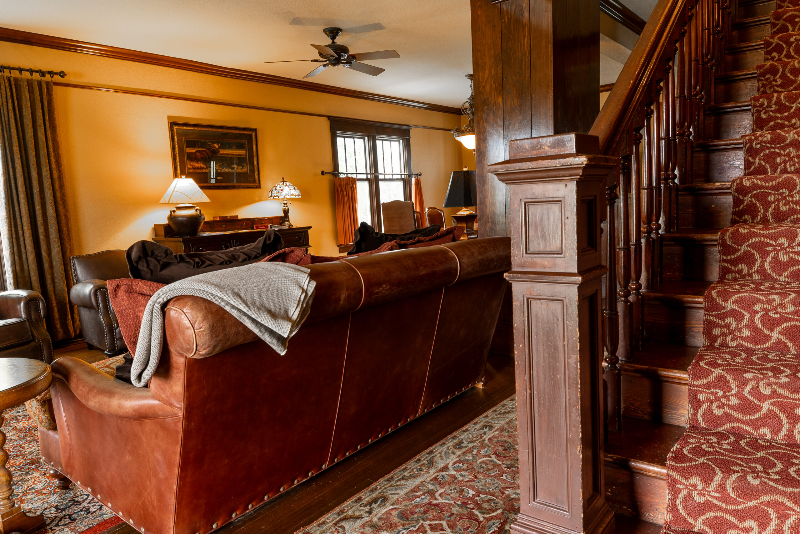 Western style living room with a leather chair and wooden staircase.