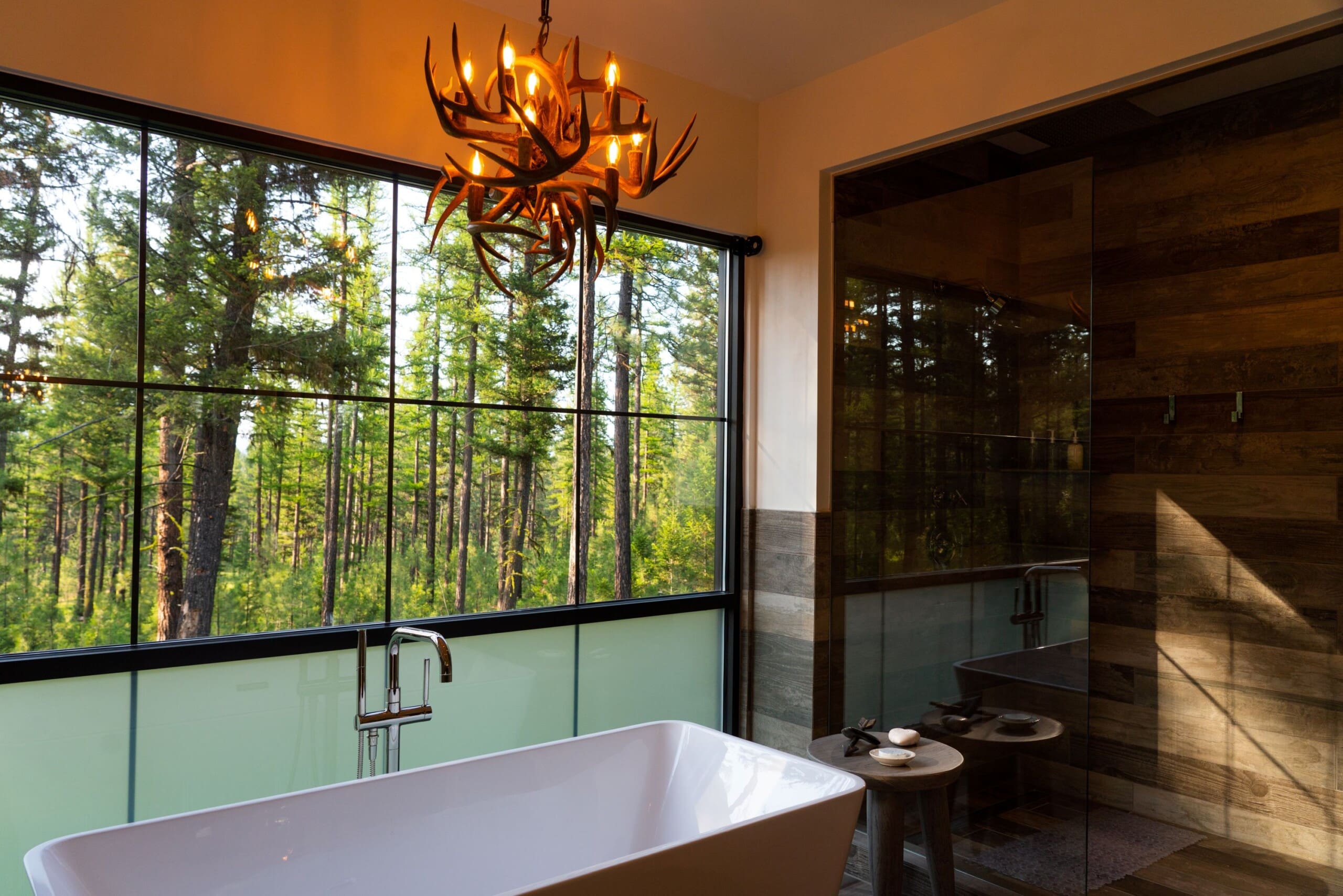 Interior of modern cabin bathroom with antler chandelier and bathtub