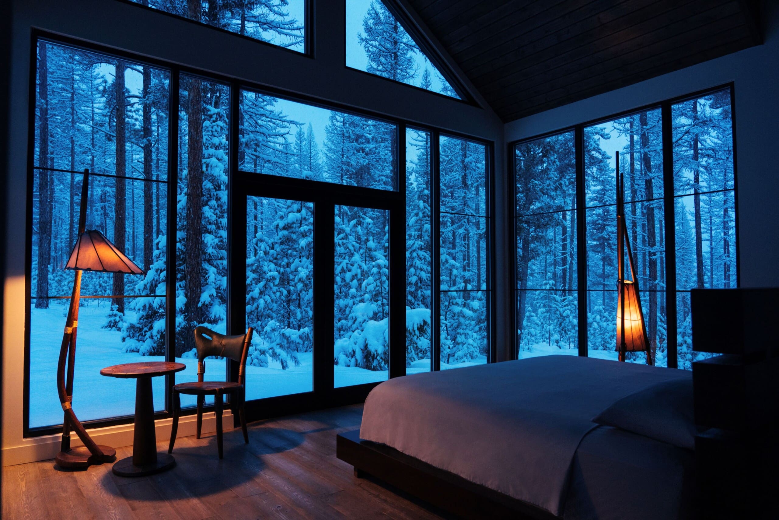 Interior of bedroom in modern cabin with snowy forest out the windows