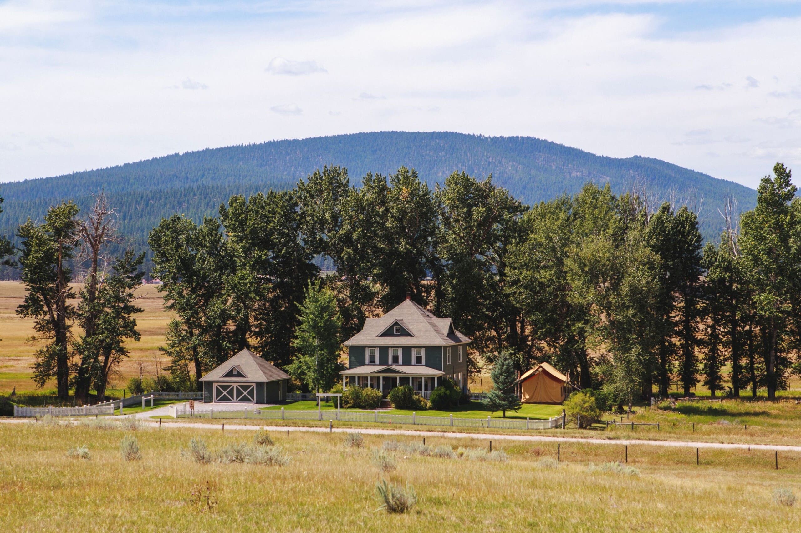 Exterior of a sage green farmhouse on a ranch