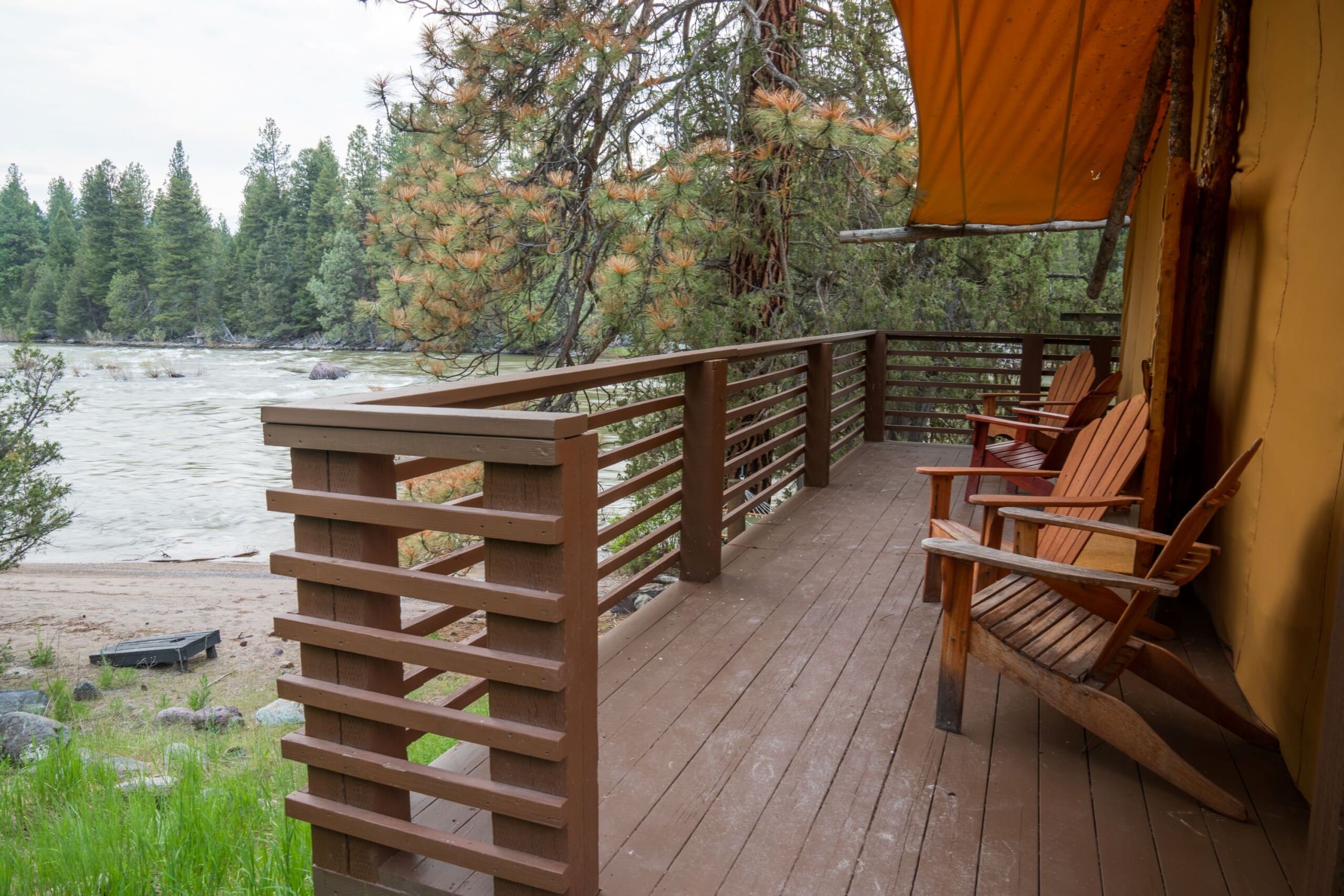 Two chairs on a glamping tent porch by a river