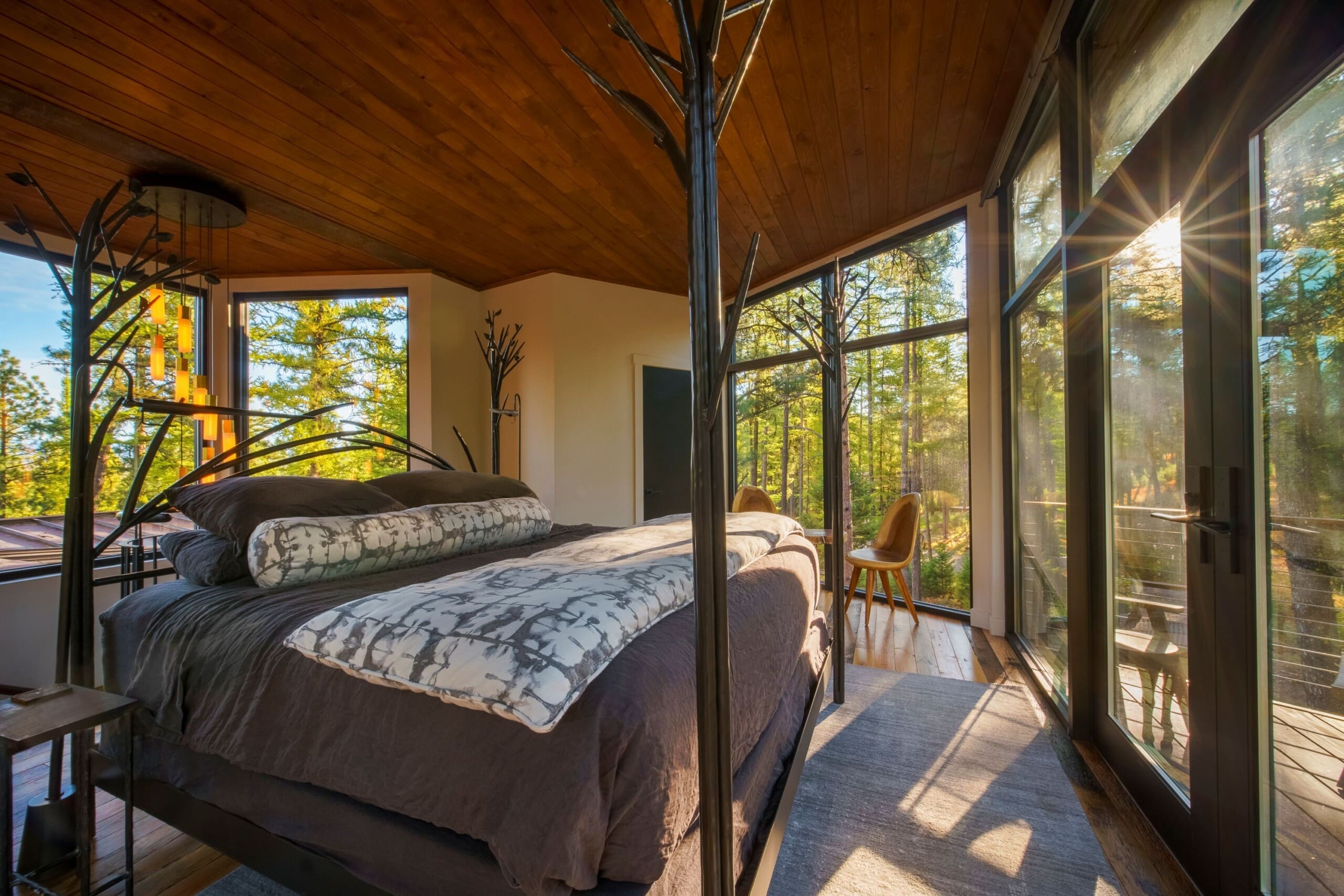 Modern interior of a treehouse cabin bedroom with forest window view and king size bed