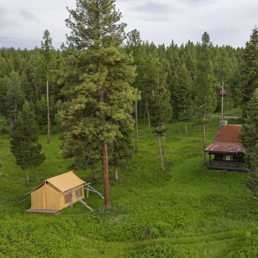Wooden cabin beside a canvas glamping tent