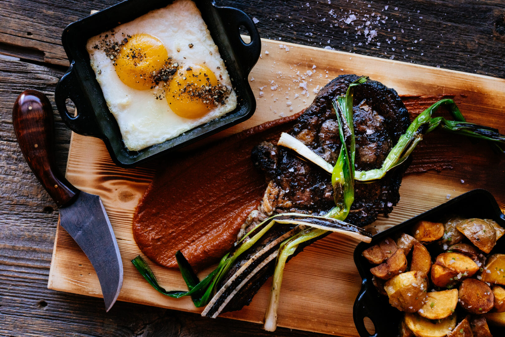 Breakfast platter of eggs, leaks, potatoes, and steak.