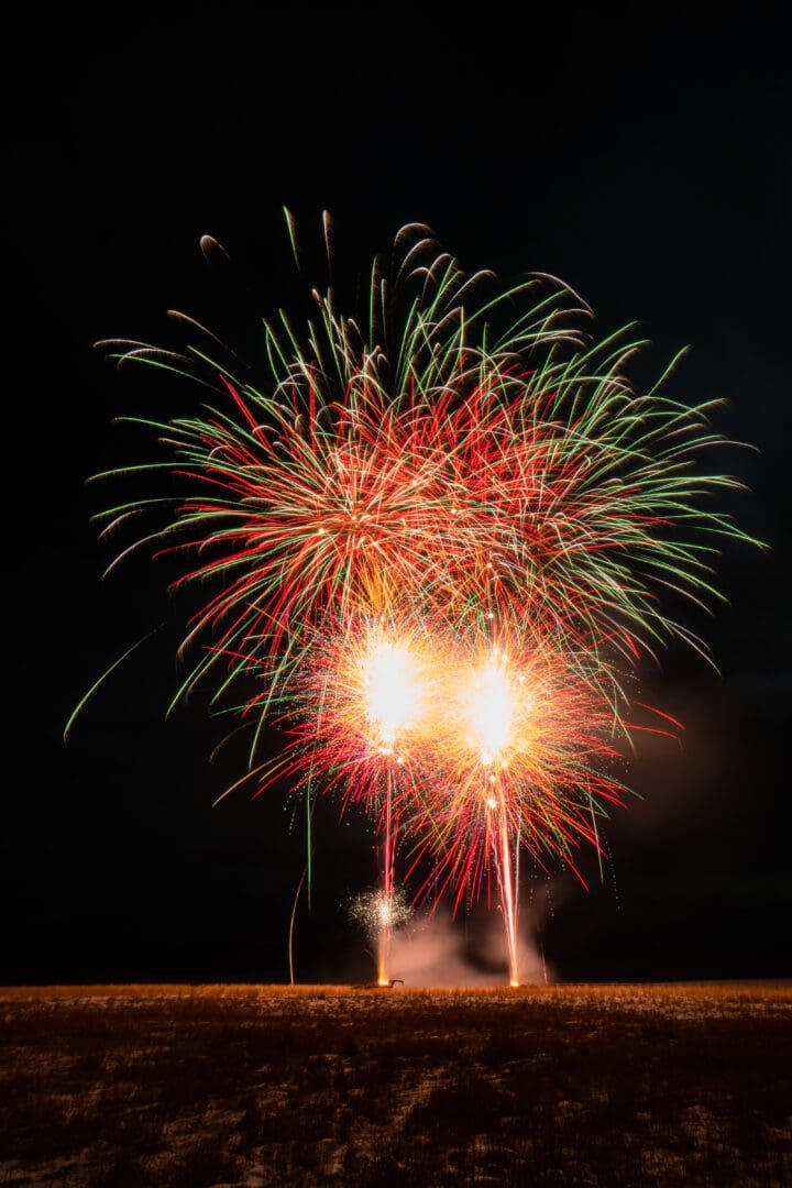 Fireworks exploding at night with snow on the ground.