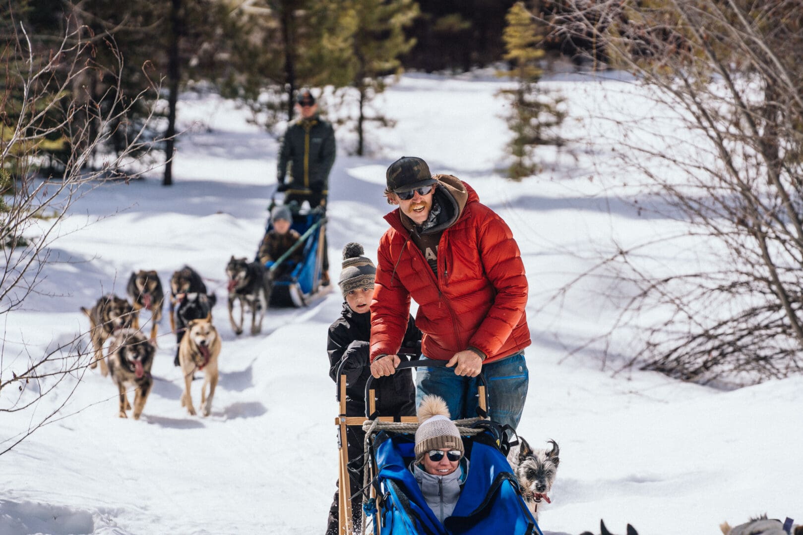Child, man, and woman on a dog-sled during the winter.