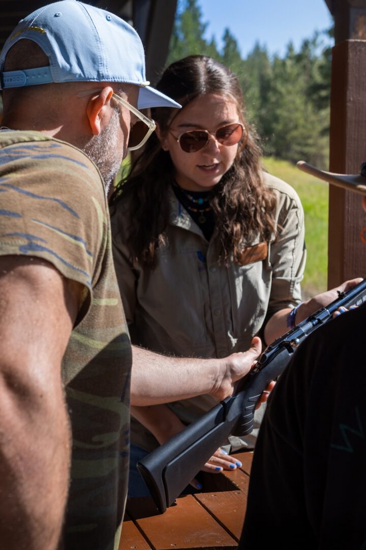 Woman showing a man a gun.