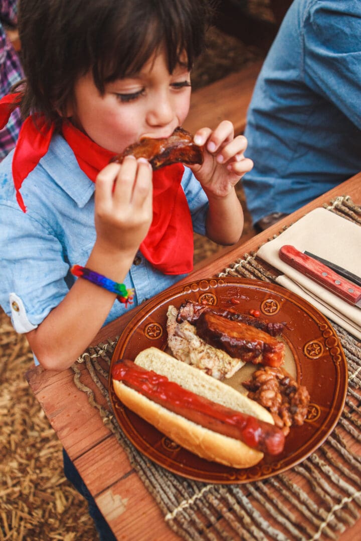 Little girl eating barbecue food with a red bandanna.