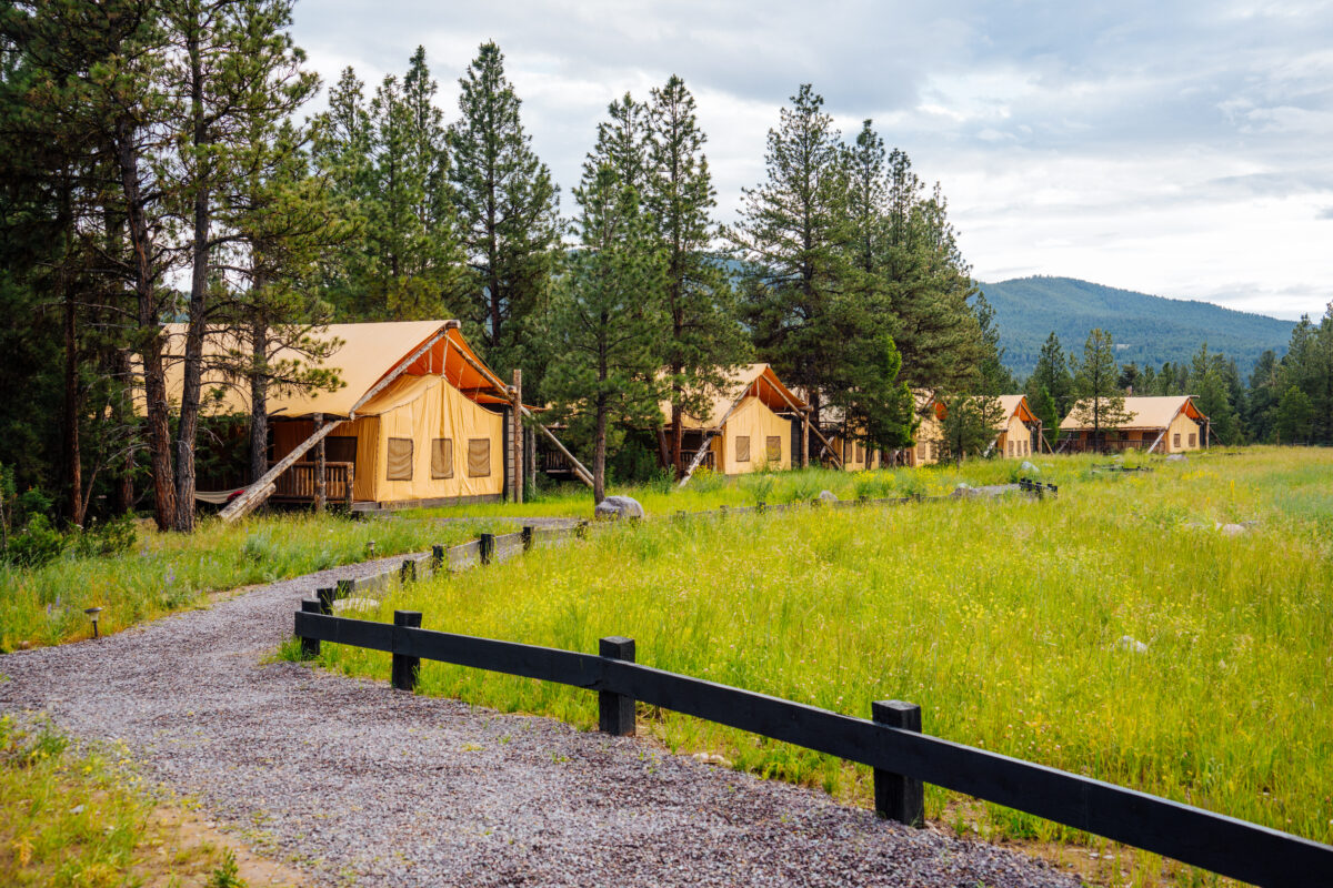 Series of tents in a line with a gravel road and fence.