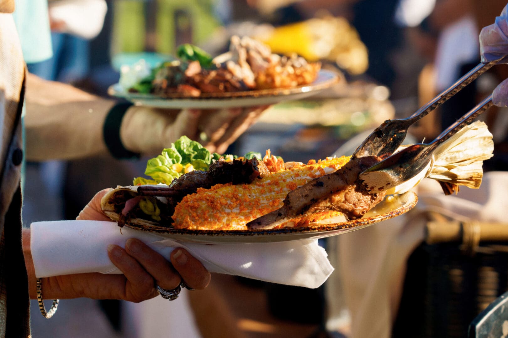 Plate of BBQ food in a line of individuals.