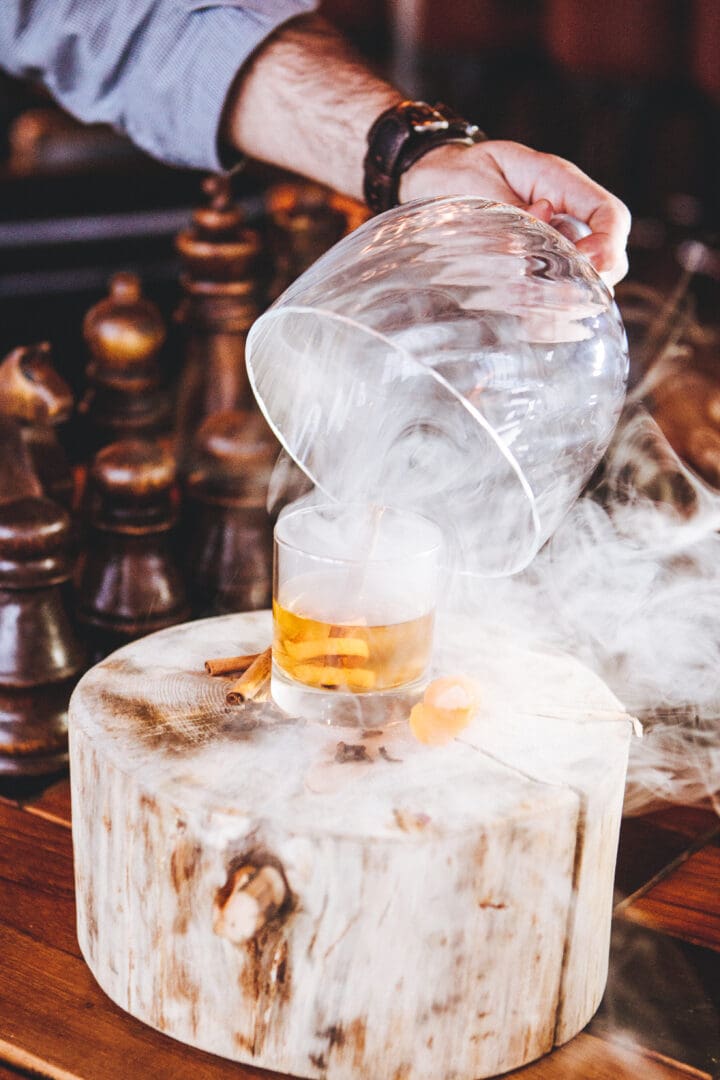 Smokey cocktail sitting on a wooden table.