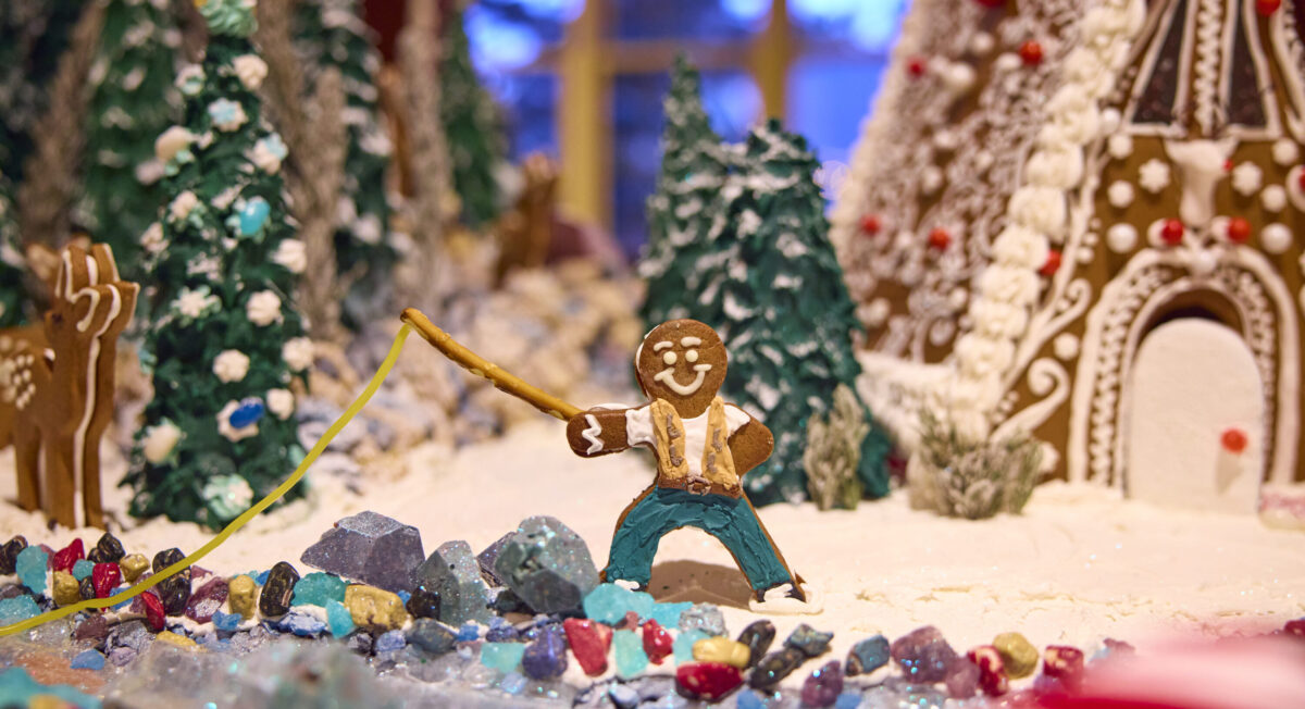 Gingerbread man fishing over a gingerbread river in his gingerbread village.