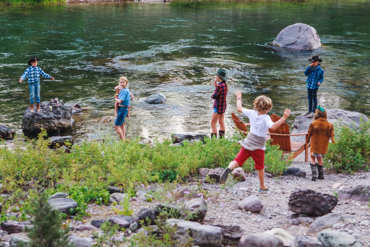 Children playing and walking around a creek in the summertime.