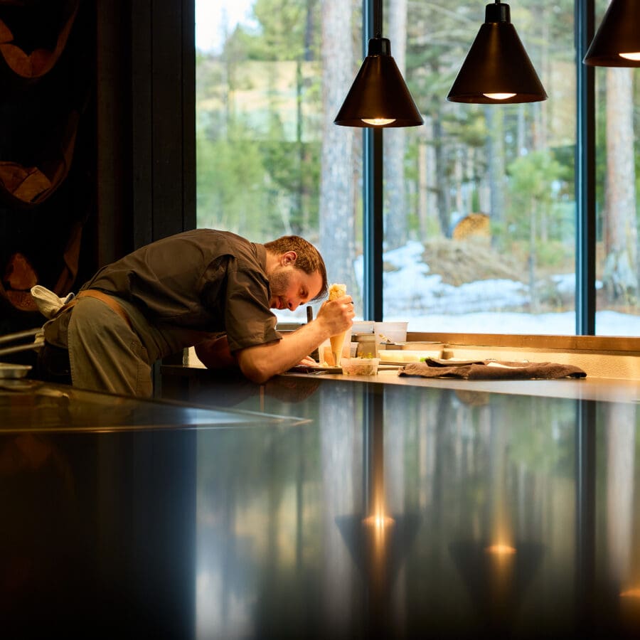 Chef working on a dish inside a darkly lit room.