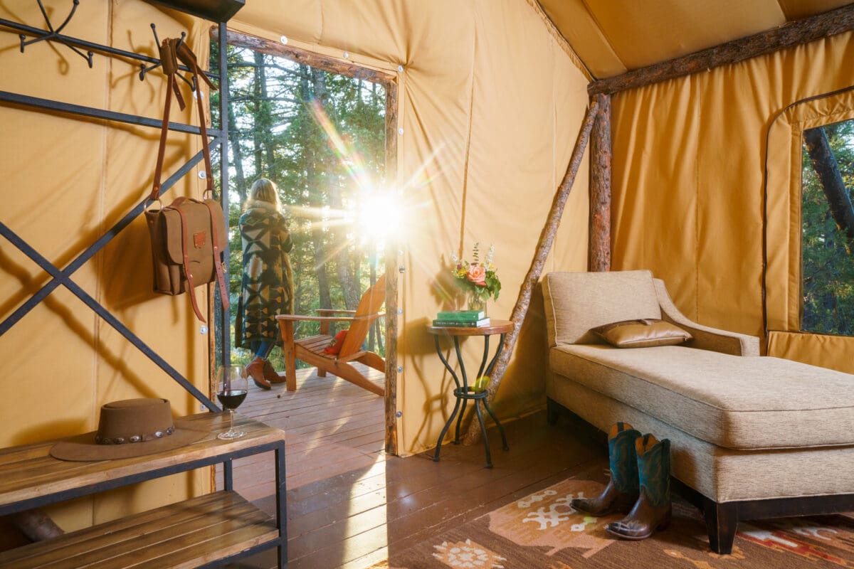 Woman stepping outside of her glamping tent that is western themed.