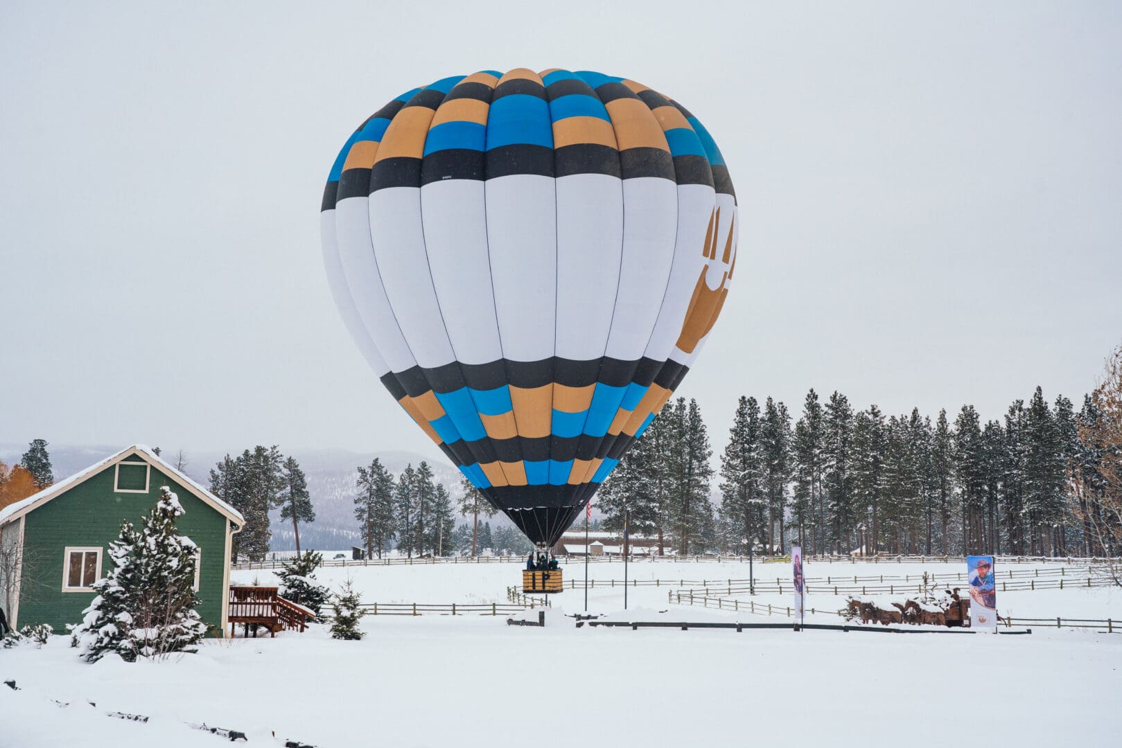 Hot air balloon sitting on a snowy field with trees behind it.