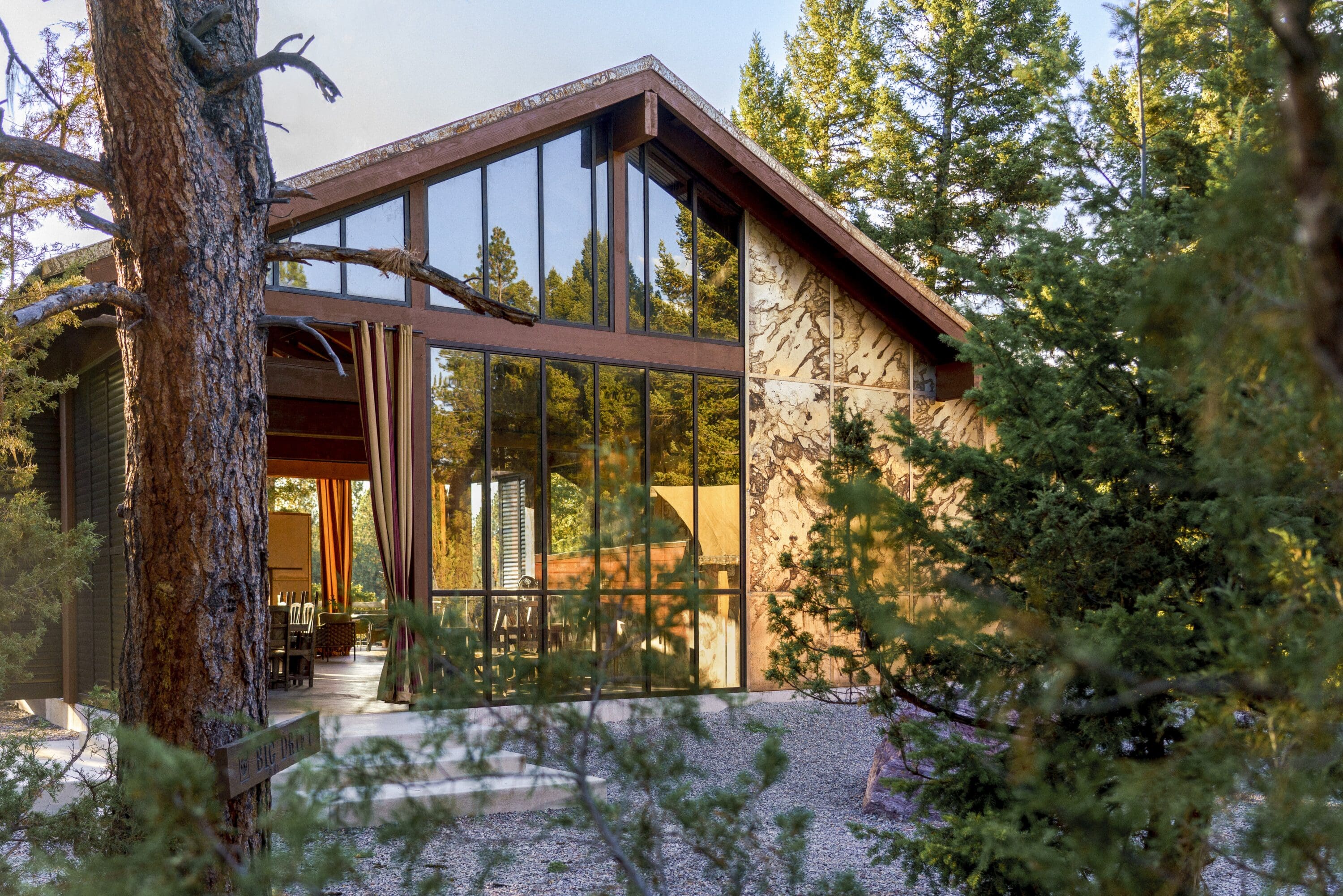 Large glass and stone building surrounded by trees.