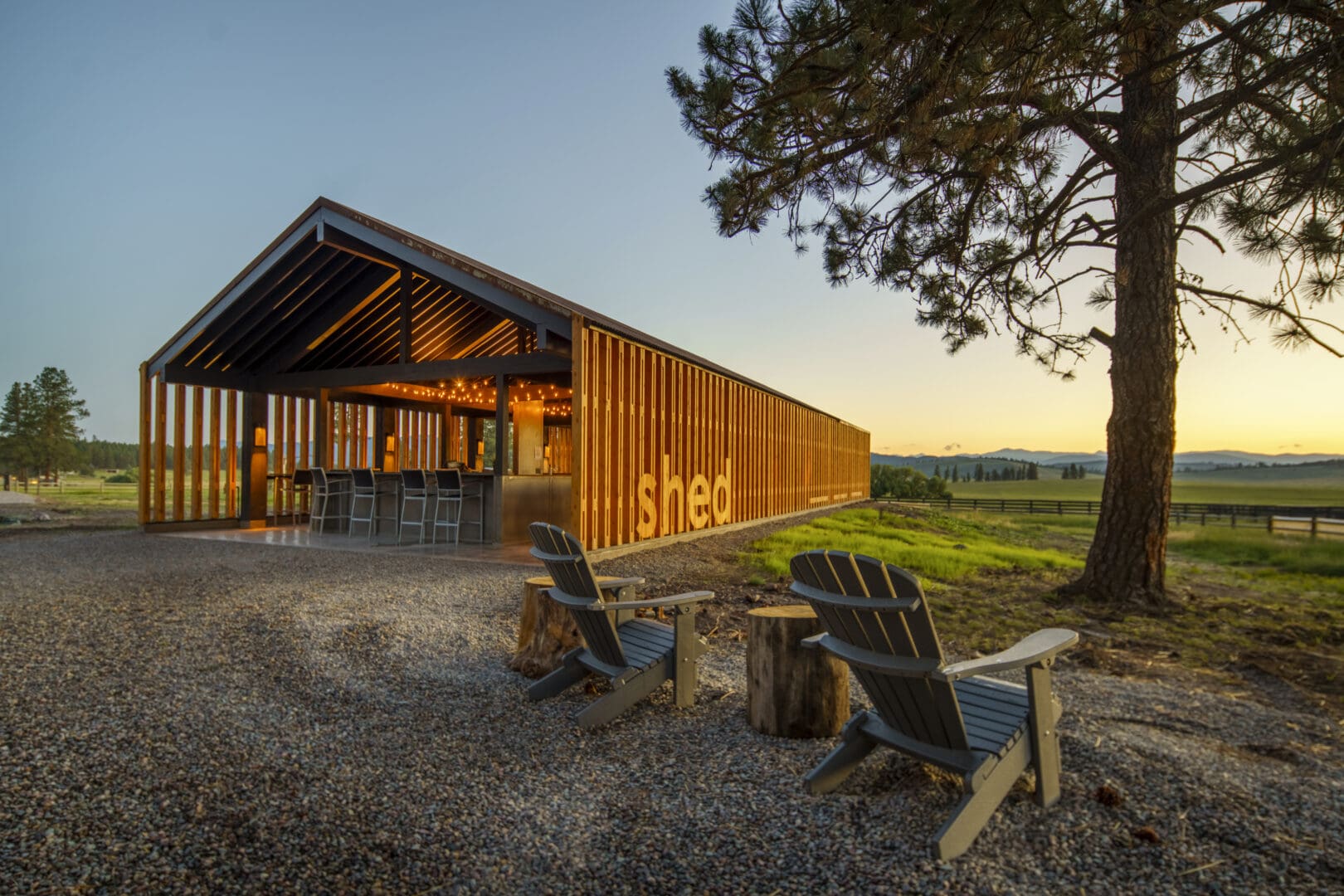 Wooden shed dining area with chairs in the front looking over at the sky.