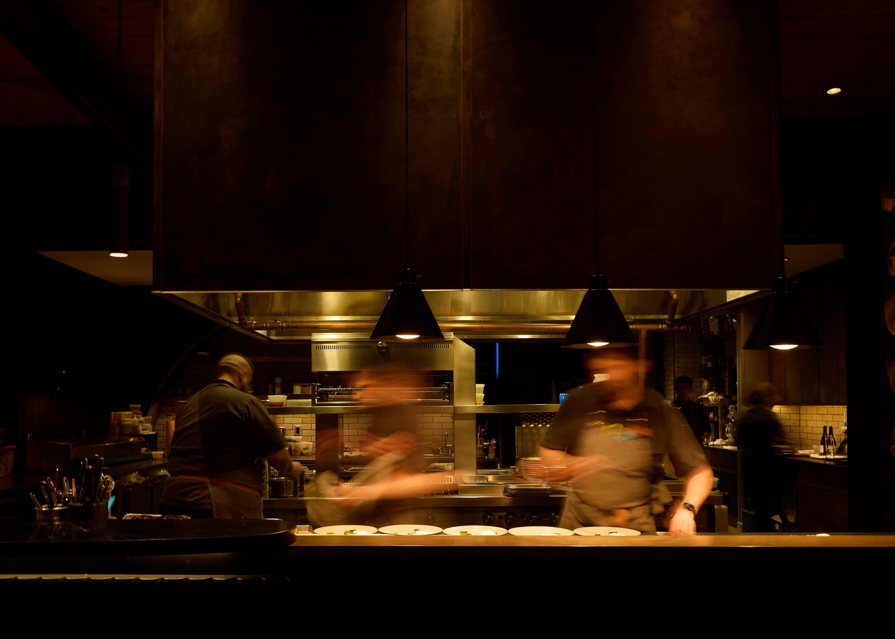 Blurry photo of chefs working inside at a dimly lit restaurant.