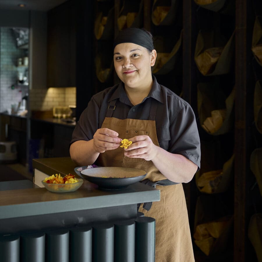 Chef holding a pastry in a dark elegant dining room.
