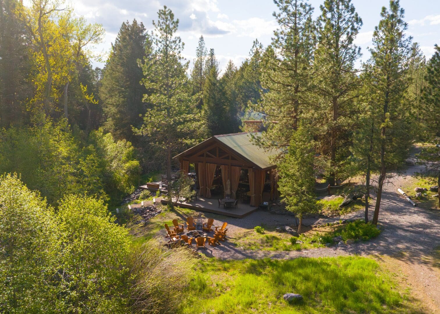 Shot of an outdoor dining pavilion surrounded by trees with chairs and a fire pit.