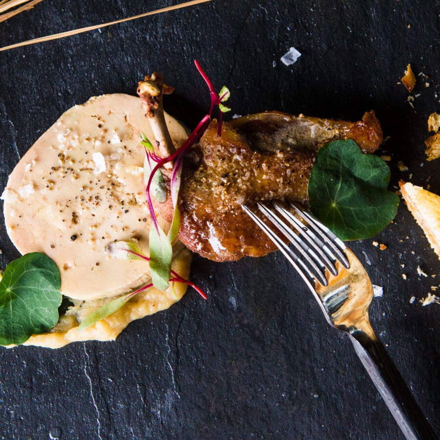 Fancy plate of meat with a cheese sauce and a fork cutting into the meat.