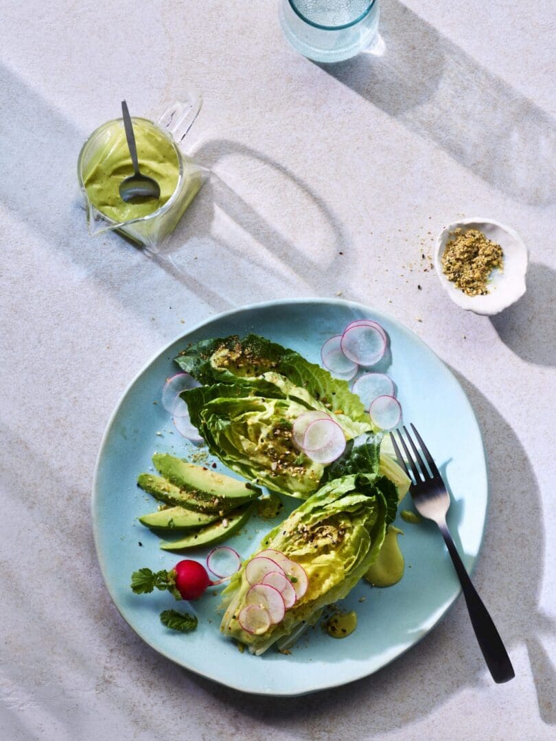 A plate with arranged lets and avocados with a drink on the side.