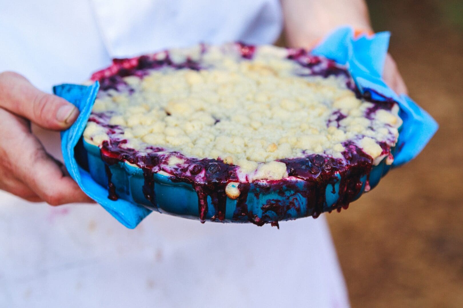 Closeup of a chef holding a blueberry pie.