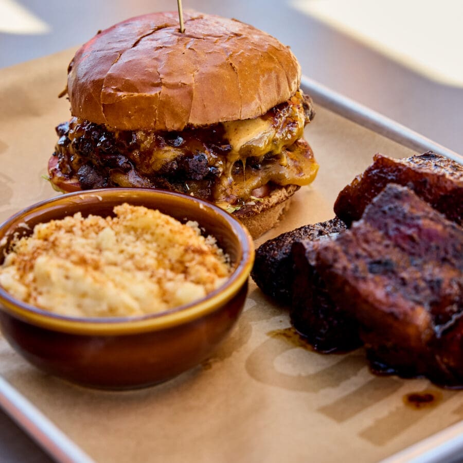 A burger, Mac and cheese, and brisket sitting on a tin tray.