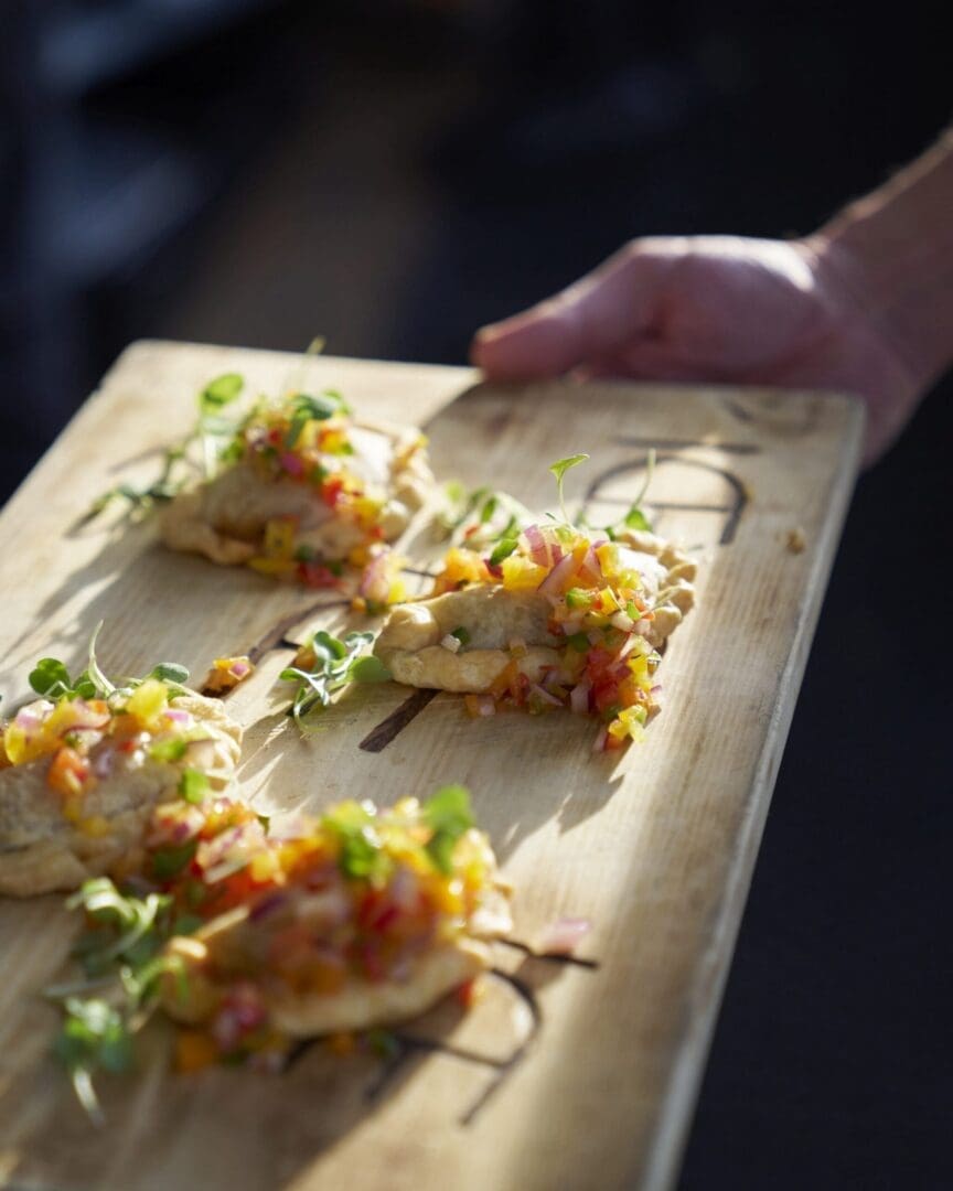 Someone holding a wooden platter of a fancy appetizer.