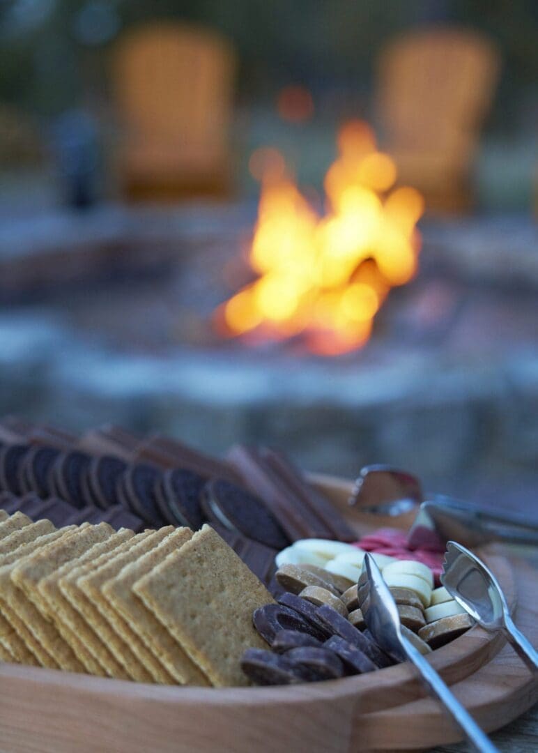 Closeup of a platter holding smores items with a fire in the background.