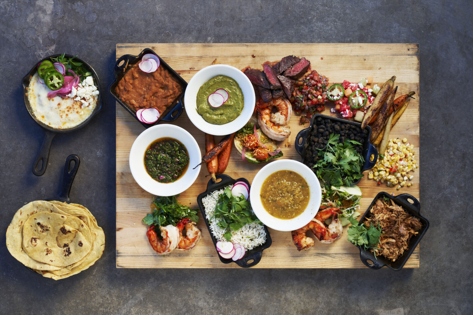 Different BBQ style food arranged on a wooden tray.
