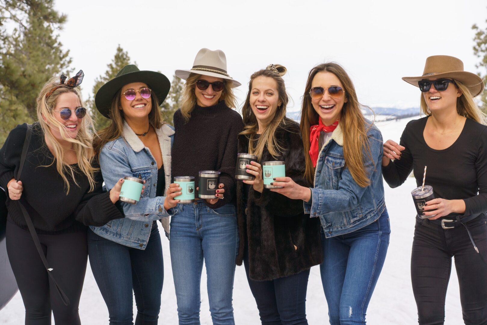Group of friends cheering drinks together outside on a snowy field.