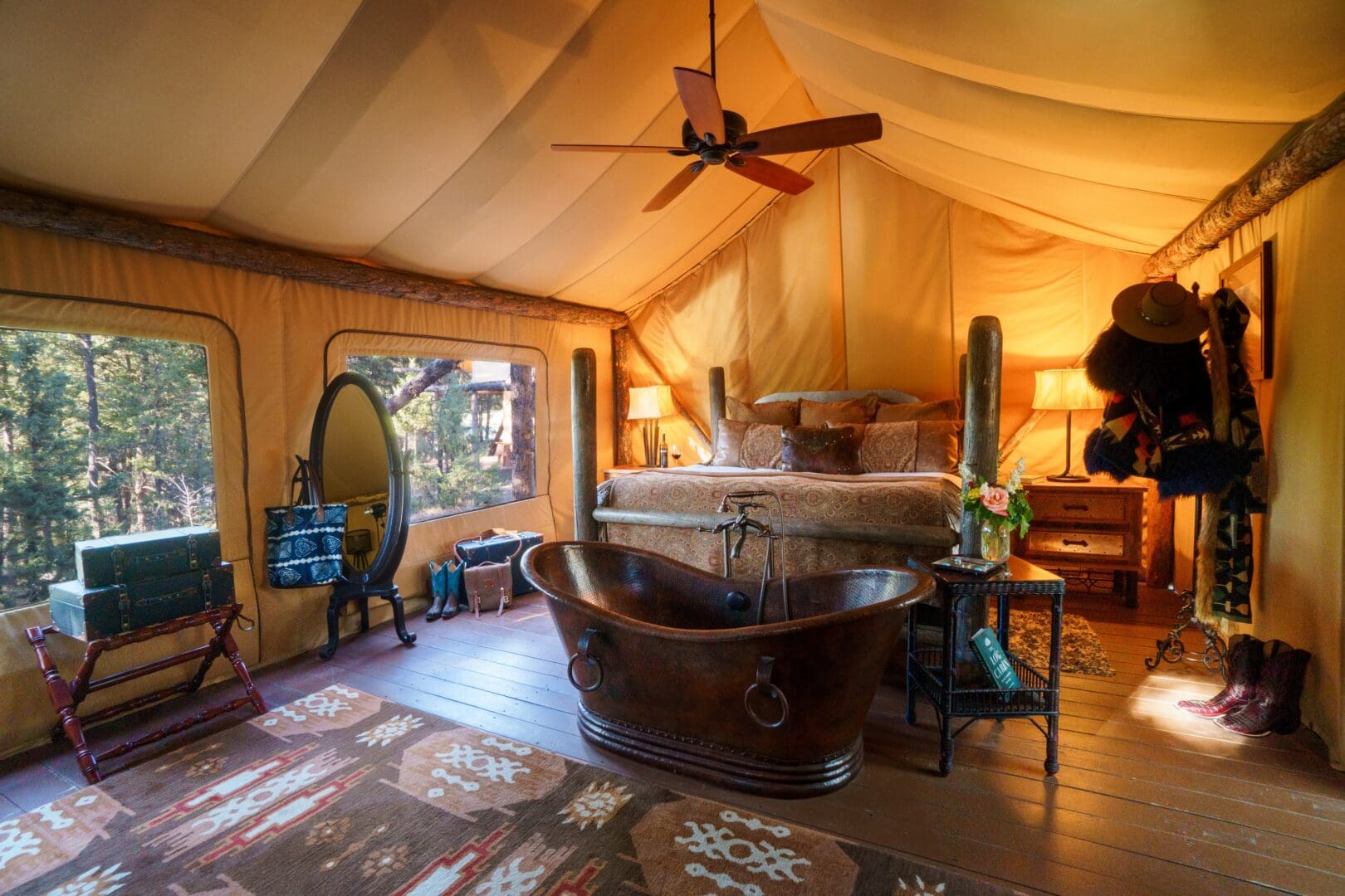 Inside of a western glamping tent with a copper tub in front of the bed.