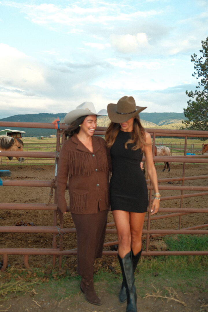 This image shows two women standing next to each other in front of a metal gate.