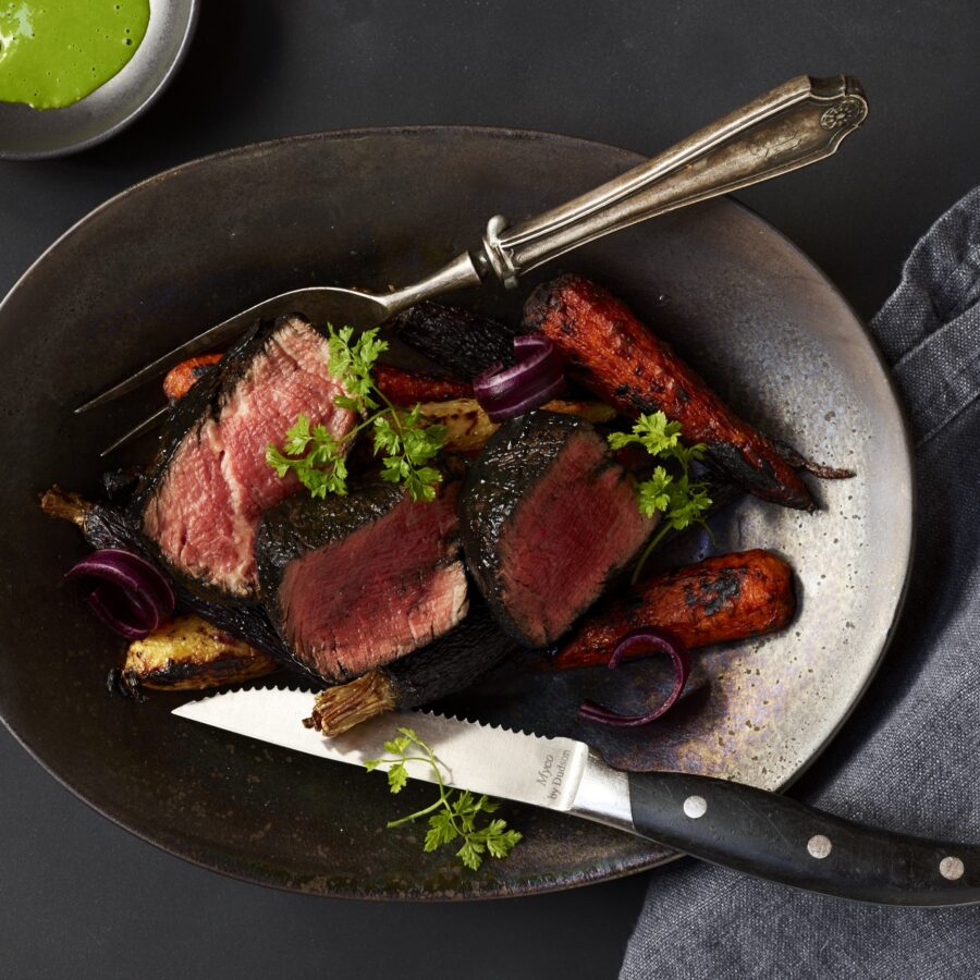 A fancy dish of cut up steak resting in a bowl with a knife and fork.