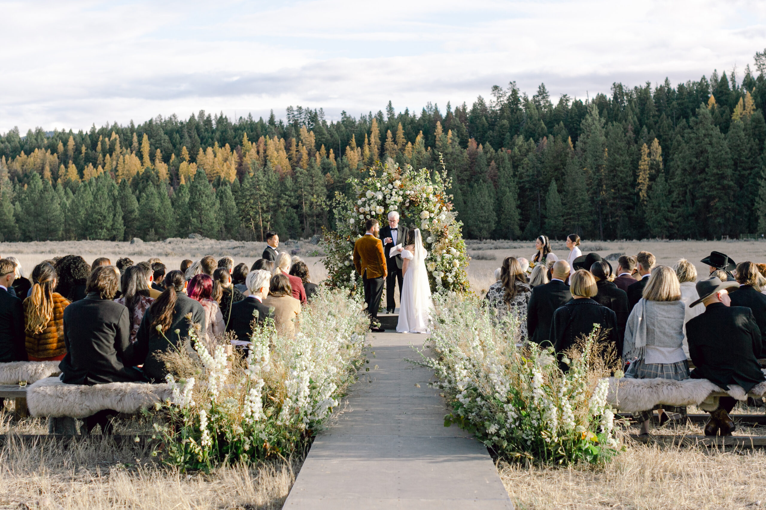 Outdoor western wedding with an aisle and the bride and groom exchanging vows.
